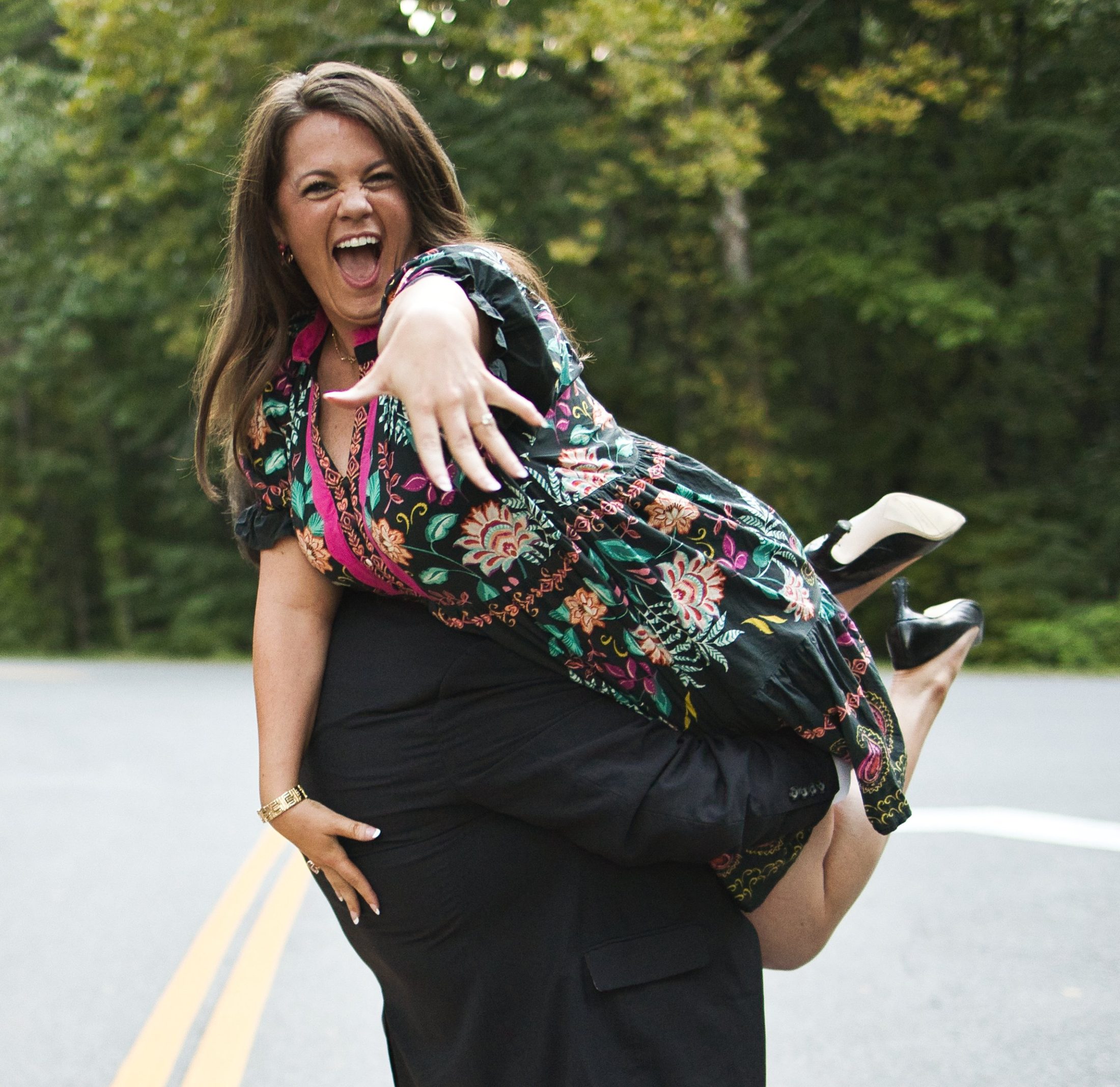 Lifted up mid-twirl on a forest road, laughing and showing off the engagement ring
